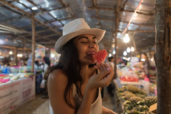 Hermosa mujer joven degustación de sandía en el tradicional mercado callejero en Asia chica turista comprar frutas frescas en Tailandia bazar — Foto de Stock