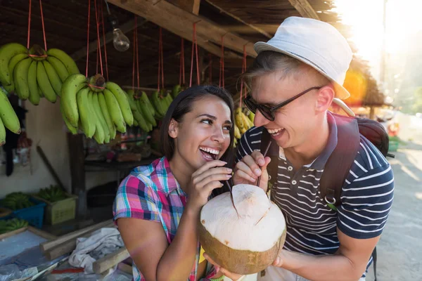 Happy Couple Drinking One Coconut On Thailand Street Market, Cheerful Tourists Man And Woman Young In Traditional Fruits Bazaar In Asia — Stock Photo, Image