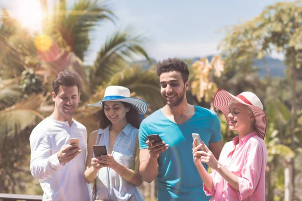 Gelukkig groep jongeren Messaging met cel Smart Phones buiten op het zomerterras met Tropical Forest View Mix Race mannen en vrouwen — Stockfoto