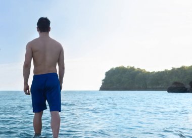 Adam plaj yaz tatili, genç adam Stand su arka arka görünümü