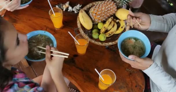 Menschen essen leckere Nudelsuppe asiatisches Essen, Freunde Gruppe füttern einander sitzen an der Tischplatte Winkel Ansicht — Stockvideo