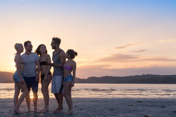 日没の夏季休暇のご若い人ビーチのグループは海辺を歩いて幸せ笑顔の友人 — ストック写真
