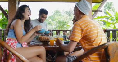 Konuşan insanlar yemek Noodles, arkadaş grubu tropik orman manzaralı terasta masaya oturmak