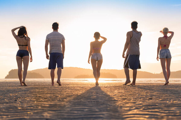 Young People Group On Beach At Sunset Summer Vacation, Friends Walking Seaside Back Rear View