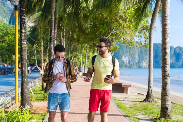 Dois homens usando celulares inteligentes Parque tropical casal conversando férias on-line mar férias de verão — Fotografia de Stock