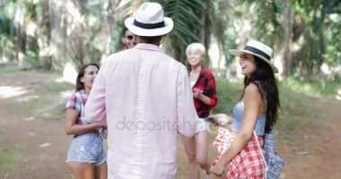 İnsanlar grubu hücre kullanarak konuşan sırt çantaları ile akıllı telefonları, erkek ve kadın tropikal palmiye ağacı ormanda yürüyüş gülüyor