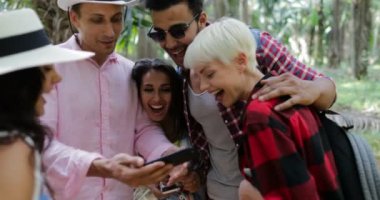 İnsanlar grubu hücre kullanarak konuşan sırt çantaları ile akıllı telefonları, erkek ve kadın izle Fotoğraf tropikal palmiye ağacı ormanda yürüyüş üzerinde