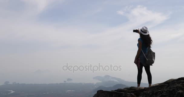 Dívka pořizování fotografie krajiny z vrcholu hory na chytrý mobil, ženské Turistický batoh stojící na útesu vychutnat ranní Panorama — Stock video
