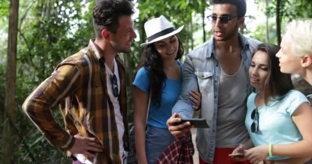 Grupo de turistas perdidos en el bosque Mapa de uso en el teléfono celular Senderismo Mix Race Personas Mochileros en el camino Caminando — Vídeos de Stock