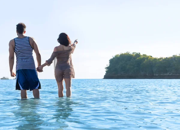 Ζευγάρι στην παραλία καλοκαιρινές διακοπές, ο άνθρωπος γυναίκα στο νερό σημείο δάχτυλο αντίγραφο χώρο όμορφη νεαρή κοπέλα ο τύπος πίσω πίσω όψη — Φωτογραφία Αρχείου