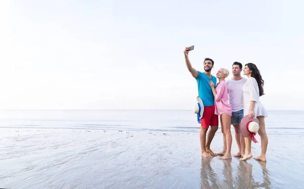 Группа молодых людей на пляже делает селфи фото на мобильном смартфоне Летние каникулы, счастливые улыбающиеся друзья Морской праздник — стоковое фото