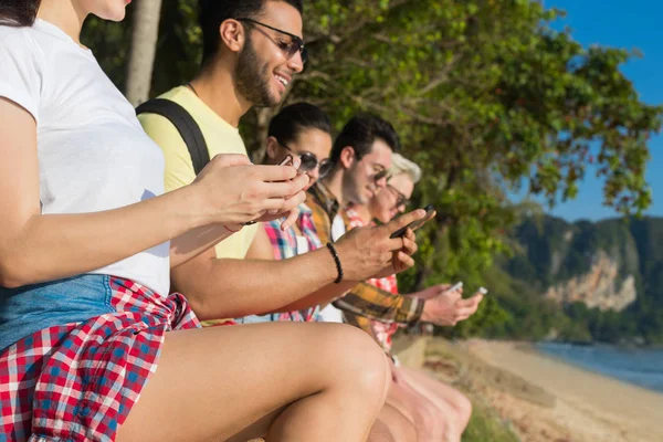 年轻人们组使用单元格智能电话热带公园棕榈树朋友聊天在线假日海暑假 — 图库照片