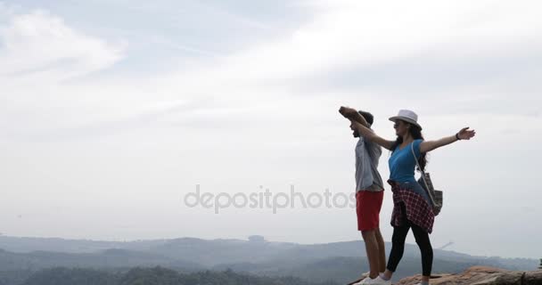 Pár turista a hegy tetejére emelt kézzel élvezni a szabadság boldog férfi és a nő keresi a táj Skyline — Stock videók