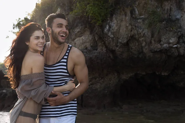 A sziklás tengerpart, nyaralás, gyönyörű fiatal boldog emberek a szeretet, a férfi és a nő mosolyog, kézen pár — Stock Fotó