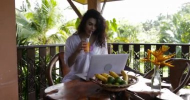 Genç kız kullanma Laptopn bilgisayar yaz terasında Kahvaltı, güzel Womantypung suyu içme sırasında klavye sırasında