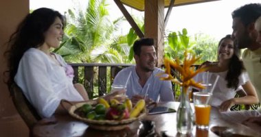 Neşeli grup arkadaşıyla oturan kızartma suyu gözlük yaz terasında, mutlu gülümseyerek Mix yarış insanlar birlikte kahvaltı masa