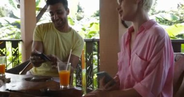 Bir grup insan kullanarak akıllı telefonlar cep konuşurken oturup birlikte masada açık havada, Teras sörf Internet üzerinden Online sohbet arkadaş