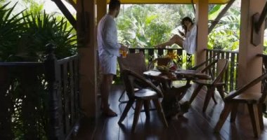 Adamı balkon, mutlu çift yaz terasında konuşurken oturan genç kadın kullanım akıllı telefonu için suyu getir