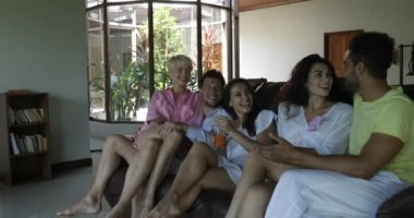 Bir grup insan konuşan Koç üzerinde oturma odasında oturup, Mix yarış arkadaşlar sohbet birlikte neşeli gülmek