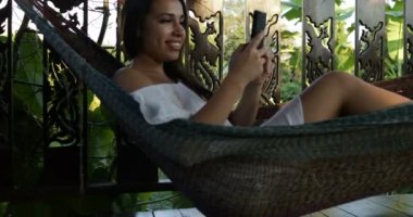 Genç kadın dokunmatik cep akıllı telefon hamak Online yaz teras mutlu gülümseyen kız mesajlarında yalan