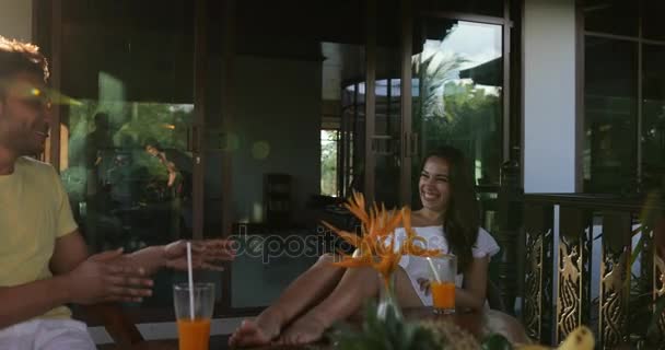 Cheerful Couple Sitting At Table On Terrace Talking, Happy Man And Woman Cheering With Juice Glasses Smiling — Stock Video