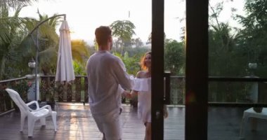 Genç çift, mutlu bir adam ve açık havada kucaklayan aşık kadın etrafında dönen güzel günbatımı manzara ile terasta çekip