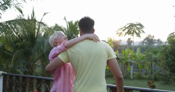 Feliz pareja girando en terraza abrazando al atardecer al aire libre mezcla raza hombre y mujer alegre mirando paisaje — Vídeos de Stock