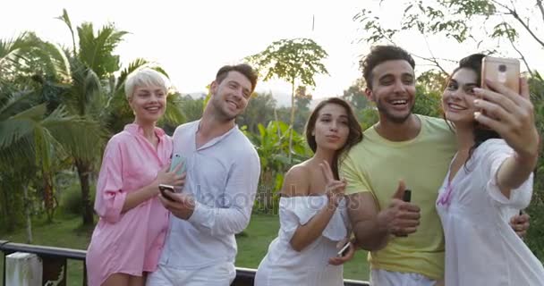 Grupo de amigos tomando foto selfie en el teléfono inteligente celular en la terraza de verano sobre el paisaje del atardecer, amigos posando para autorretrato al aire libre — Vídeo de stock