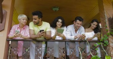 Genç grup arkadaşıyla Stnd otel balkonunda, Mix yarış insanlar Online sohbet mesajlaşma Modern araçları kullanma