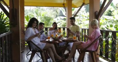 Yaz terası, Mix yarış Erkekler ve kadınlar gadget'lar Web sörf Holding masada ileti Sititng bir grup insan hücre akıllı telefonları