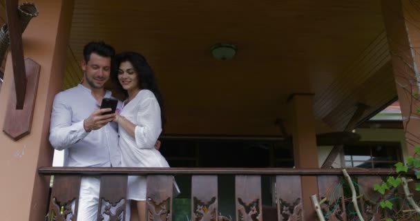 Young Man And Woman Gunakan Cell Smart Phone On Balcony In Hotel, Happy Smiling Couple Embracing Surfing Internet Together — Stok Video