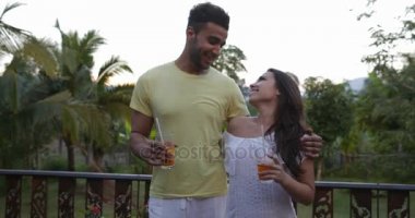 Terasta açık havada günbatımı manzara, genç farklı erkek ve kadın üzerinde konuşurken kucaklayan mutlu çift