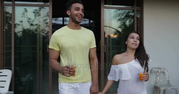 Молодая пара выйти на террасу, держа за руки говорить смотреть на закат пейзаж, счастливый разнообразный мужчина и женщина на открытом воздухе — стоковое видео