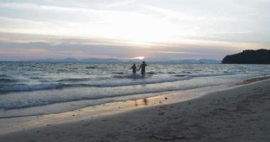 Mutlu çift su sahilde elele günbatımı genç erkek ve kadın, yaz tatili üzerinde çalıştırmak