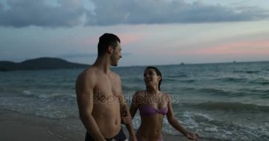 Genç çift Twilight konuşan turistler Sahilde yürüyüş tutuşup erkek ve kadın birlikte sahil üzerinde