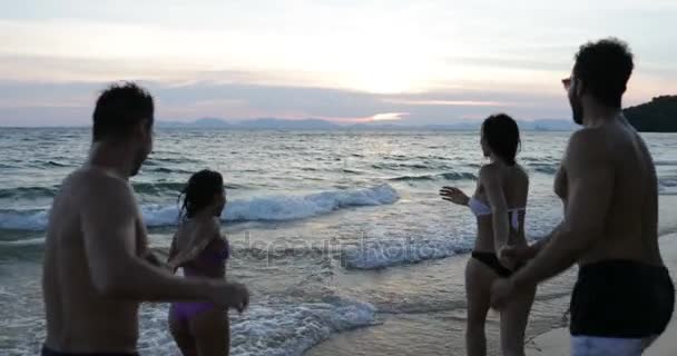 两对夫妇 Runninc 中海手牵着手在日落、 混合种族集团的人在一起度假在海边的沙滩上 — 图库视频影像