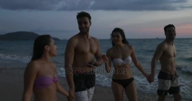 Grup günbatımı Pov kumsalda, genç insanlar mutlu gülümseyen yürüyüş deniz yaz tatili sırasında denizde konuşan arkadaşlar
