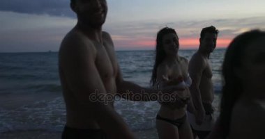 Grup günbatımı Pov kumsalda, genç insanlar mutlu gülümseyen yürüyüş deniz yaz tatili sırasında denizde konuşan arkadaşlar