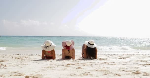 Back Rear View of Three Girls Lying On Beach Raising Legs, Enjoy Sun Tan, Woman Tourists On Summer Holiday — стоковое видео