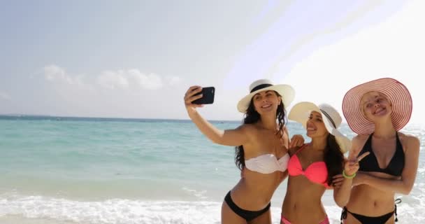 Девушки на пляже с селфи фото на телефоне смартфон, веселые женщины в Бикини снимая Соломенные шляпы на летних каникулах — стоковое видео