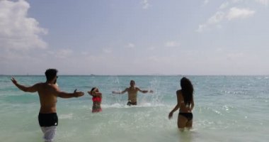 İnsanlar, kumsalda eğleniyor su sıçramasına neşeli erkek ve kadın turist tatil grubu