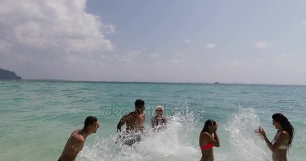 Gente salpicando en el agua divirtiéndose en la playa, hombres alegres y mujeres turistas de grupo en vacaciones — Vídeos de Stock