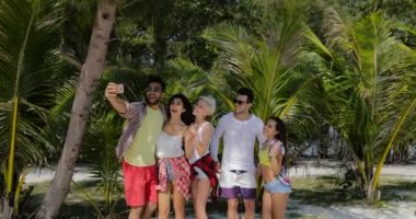 Tropik tatil palmiye ağaçları, erkek ve kadın turist altında sahilde akıllı cep telefonuyla Selfie fotoğraf almak insanlar grubu