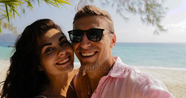 Pareja tomando foto selfie en celular teléfono inteligente en playa besos, feliz sonriente hombre y mujer Toursits en amor en vacaciones — Vídeo de stock