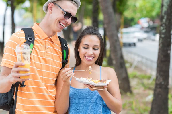 Jovem casal de turistas comer comida asiática rua andando no parque turistas alegres homem e mulher em férias — Fotografia de Stock