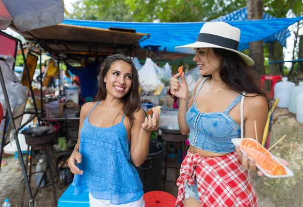 Két nők turisták eszik friss gyümölcsöt, boldog, mosolygós gyalogos utcák ázsiai város vonzó a fiatal lányok nyaralni — Stock Fotó