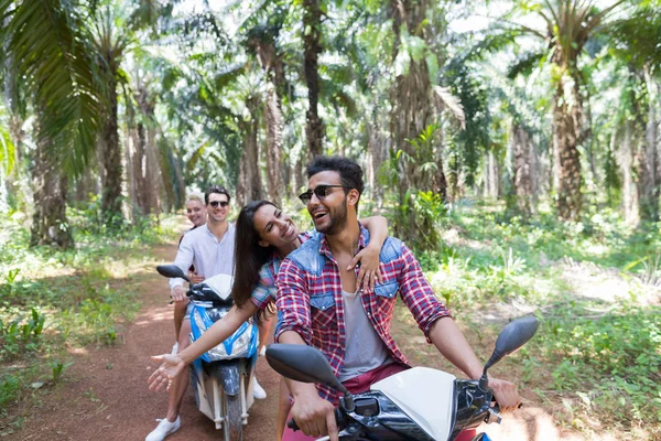 Zwei junge Paare fahren Motorroller im tropischen Wald Junge Gruppe von Menschen macht gemeinsam Roadtrip im Palmenwald — Stockfoto