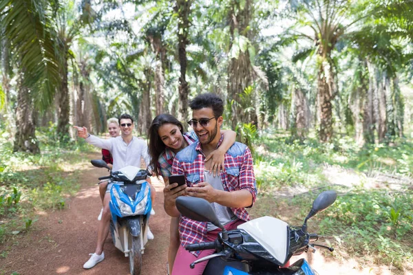 Gençler kaybolmak ve tropikal ormanda bisiklet üzerinde Scooter iki neşeli gezisinde çiftler akıllı telefon Gps harita kullanın