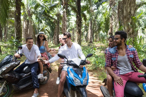 Los jóvenes usan el teléfono inteligente Mapa de GPS que viaja en bicicletas Togehter Tres parejas gratis mientras viajan por carretera en scooter en el bosque tropical — Foto de Stock