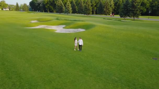 Вид с воздуха на молодую пару, прогуливающуюся по летнему парку, кружащую дрона, стреляющую мужчину и женщину — стоковое видео